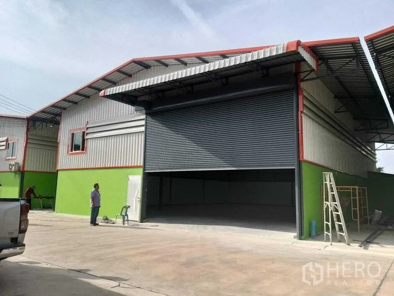 货栈 出租在Bang Khun Thian, Bangkok - 仓库正面视角，超大卷闸门与混凝土前场