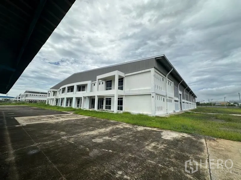 Factory for rent in Pathum Thani - Side view of factory block with two-storey office wing and lawn.