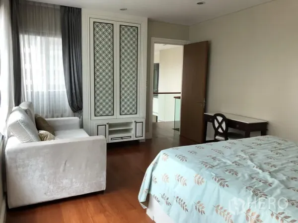 Condominium for rent or sale in Khlong Toei, Bangkok - Guest bedroom with built-in wardrobe, desk, sofa and wooden flooring.