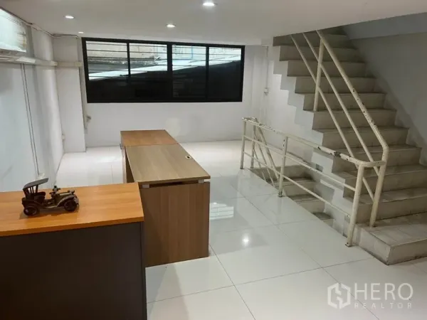 Shophouse for rent in Bang Rak, Bangkok - Open-plan upper floor with desks, large window and staircase with railings.