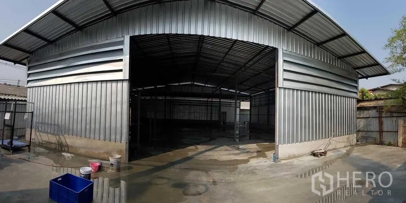 Warehouse for rent in Sai Mai, Bangkok - Front facade of the metal-clad warehouse showing a wide opening and concrete loading yard.