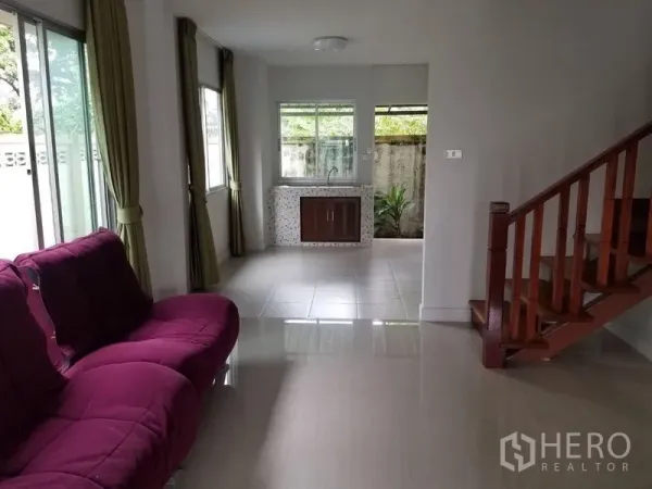 Townhouse for rent in Bang Kapi, Bangkok - Bright living room with purple sofa, tiled floors, large windows and a wooden staircase.