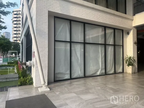 Retail Space for rent in Khlong Toei, Bangkok - Street-level facade featuring black-framed glass panels and stone-tiled plaza.