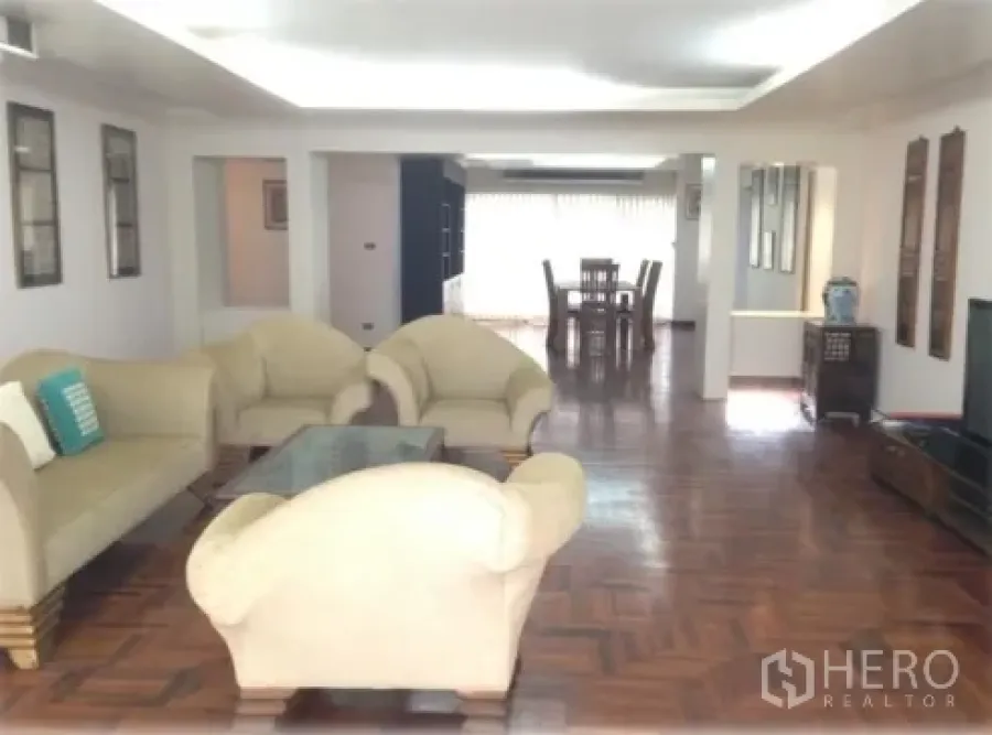 Condominium for rent in Watthana, Bangkok - Large open-plan living room with cream sofas, glass coffee table and parquet flooring leading to the dining zone.