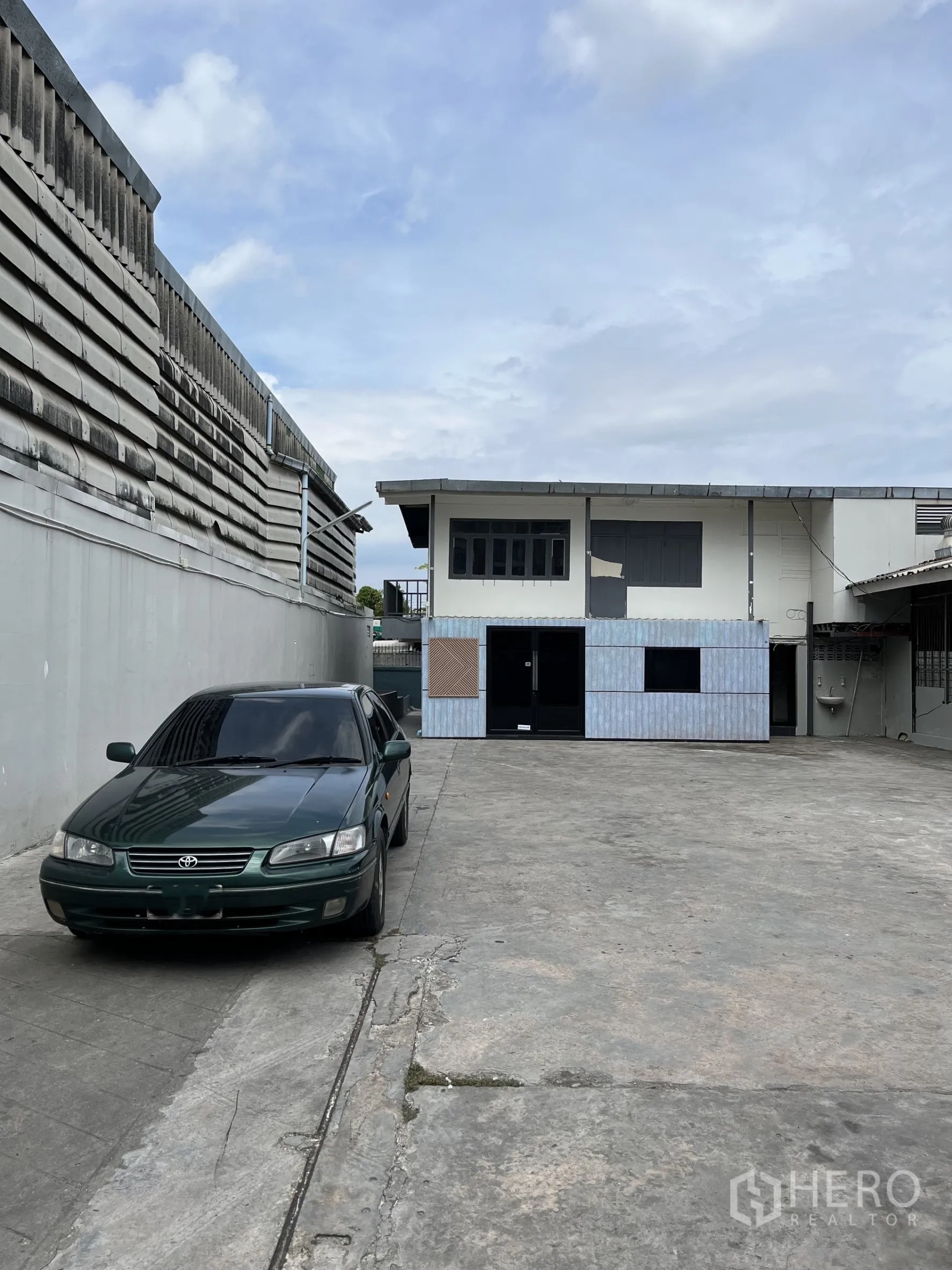 Warehouse for rent in Bangkok - Long concrete driveway leading to rear two-storey office building within the compound.