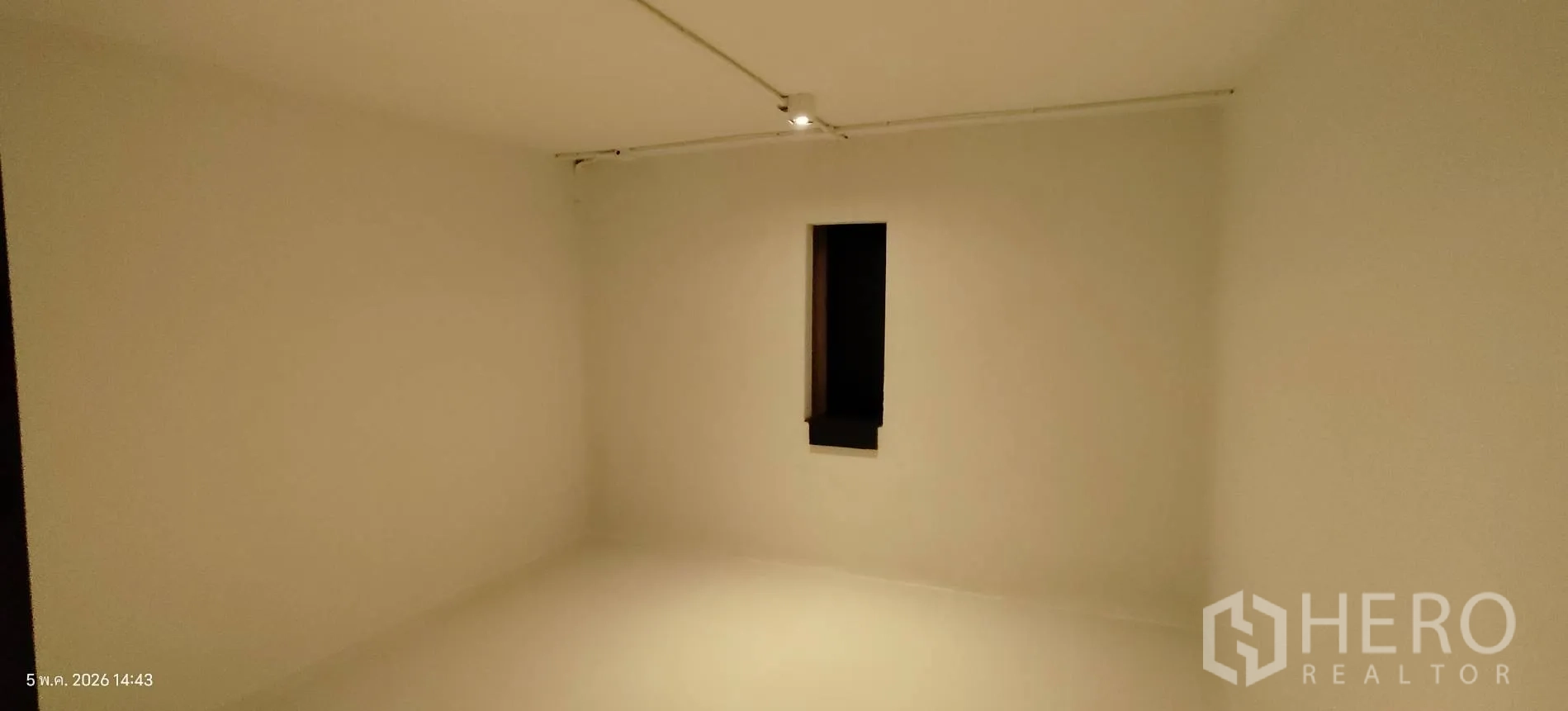 Shophouse for rent in Watthana, Bangkok - Minimal white room with a narrow vertical window and track lighting.