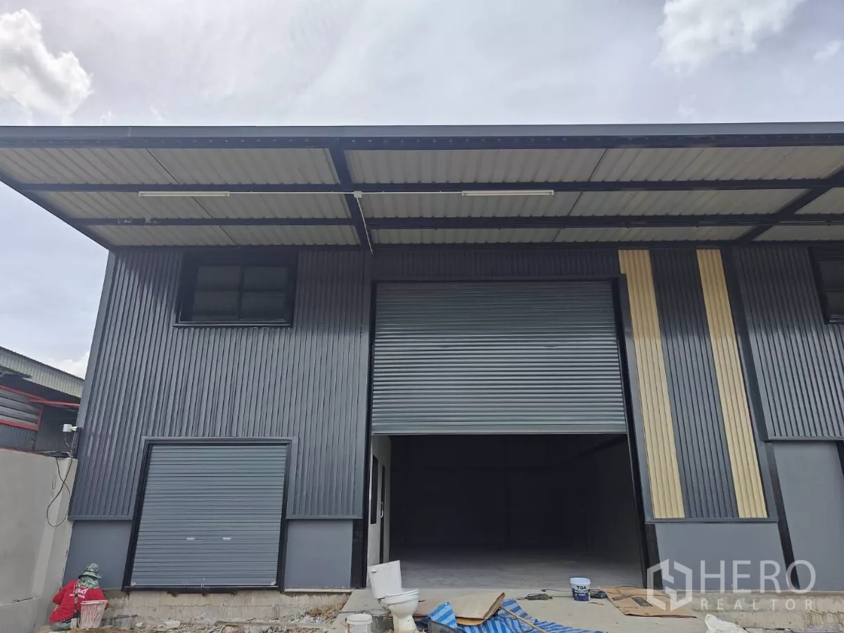 Warehouse for rent in Sam Phran, Nakhon Pathom - Modern steel-clad warehouse facade with a high roof and sheltered loading bay.