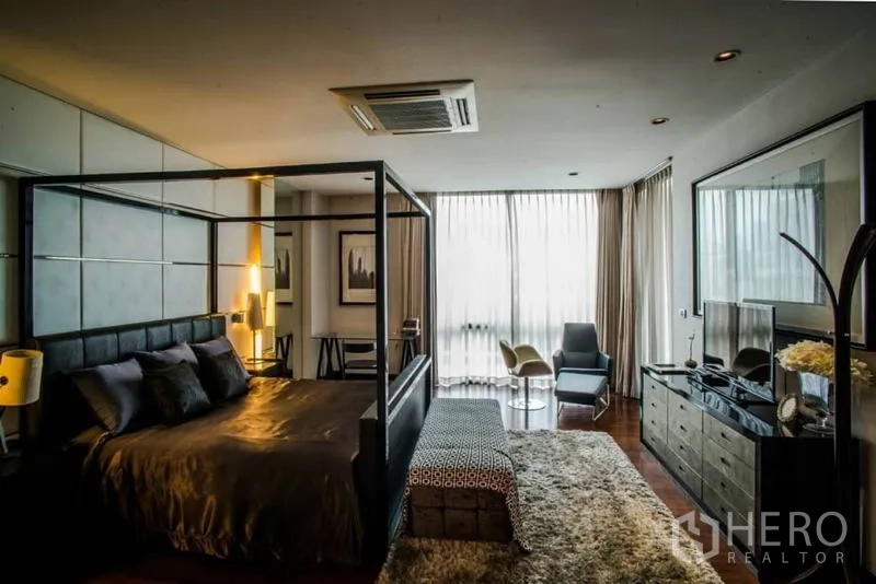 Townhouse for rent or sale in Watthana, Bangkok - Spacious master bedroom with four-poster bed, seating nook and wood floors