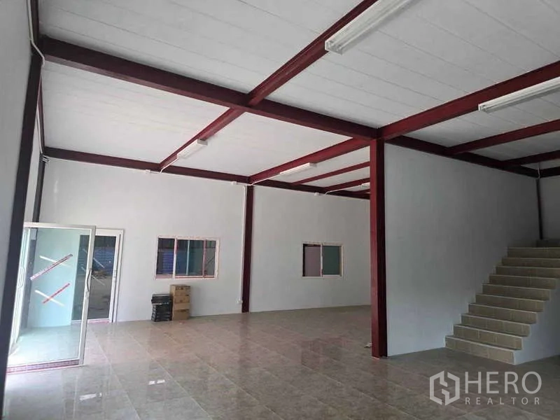 Warehouse for rent in Mueang Samut Sakhon, Samut Sakhon - Ground-floor warehouse office area with tiled floor, red steel columns, and fluorescent lighting.