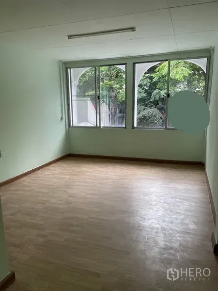 Shophouse for rent in Phaya Thai, Bangkok - Bright room with large sliding windows overlooking green trees.