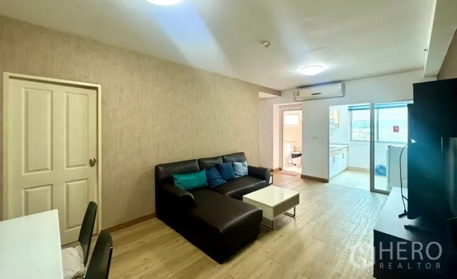 Condominium for rent in Huai Khwang, Bangkok - Open-plan living and dining area with sofa, dining table, and entry to the kitchen.
