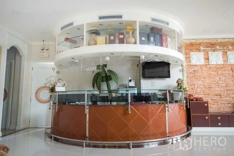 Detached House for rent or sale in Bang Kapi, Bangkok - Rounded built-in bar counter with glass shelving and mounted TV.