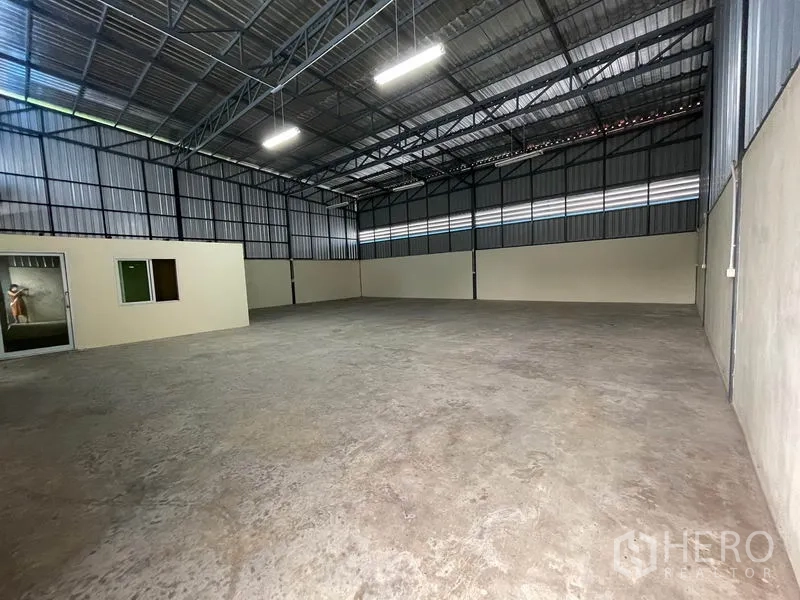 Warehouse for rent in Khlong Luang, Pathum Thani - Clear-span warehouse floor showing steel roof structure and admin room.