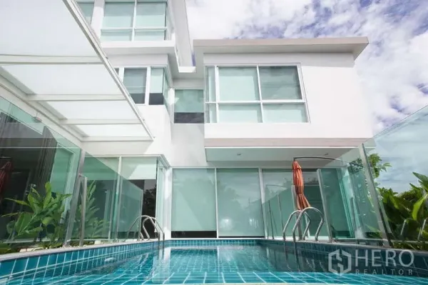 Detached House for rent in Lat Phrao, Bangkok - Close-up of the blue-tiled lap pool with glass fencing beside floor-to-ceiling windows.