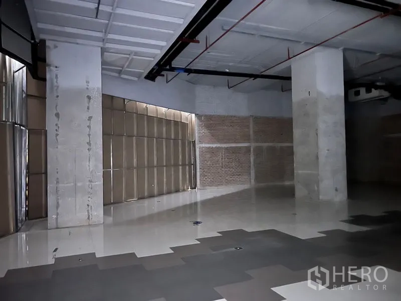 Retail Space for rent - Corner of the unit showing polished tiles, concrete pillars and visible building services.