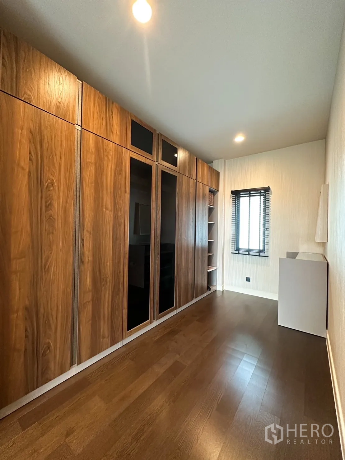 Detached House for rent or sale in Bang Kapi, Bangkok - Long walk-in closet featuring full-height wood wardrobes and recessed lighting.