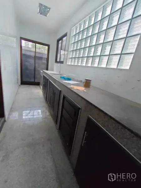 Home Office for rent in Pathum Wan, Bangkok - Bright pantry with long countertop, glass-block wall and a door to a small terrace.