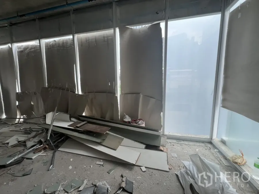 零售空间 出租 - 毛坯商铺，落地窗与施工残料可见，处于装修阶段。