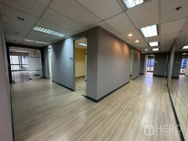 Office Space for rent in Watthana, Bangkok - Hallway with multiple glass‑door rooms and a mirrored wall on a modern office floor.