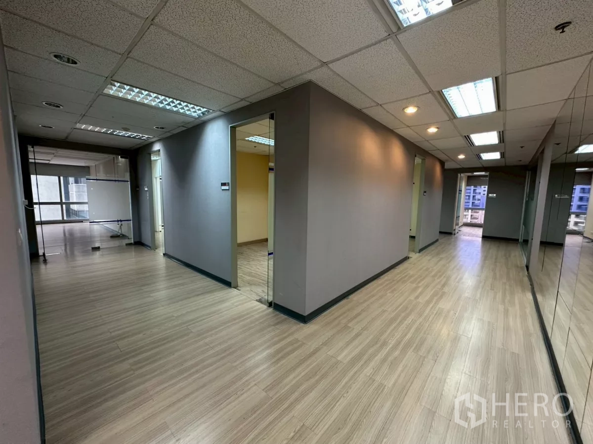 Office Space for rent in Watthana, Bangkok - Hallway with multiple glass‑door rooms and a mirrored wall on a modern office floor.