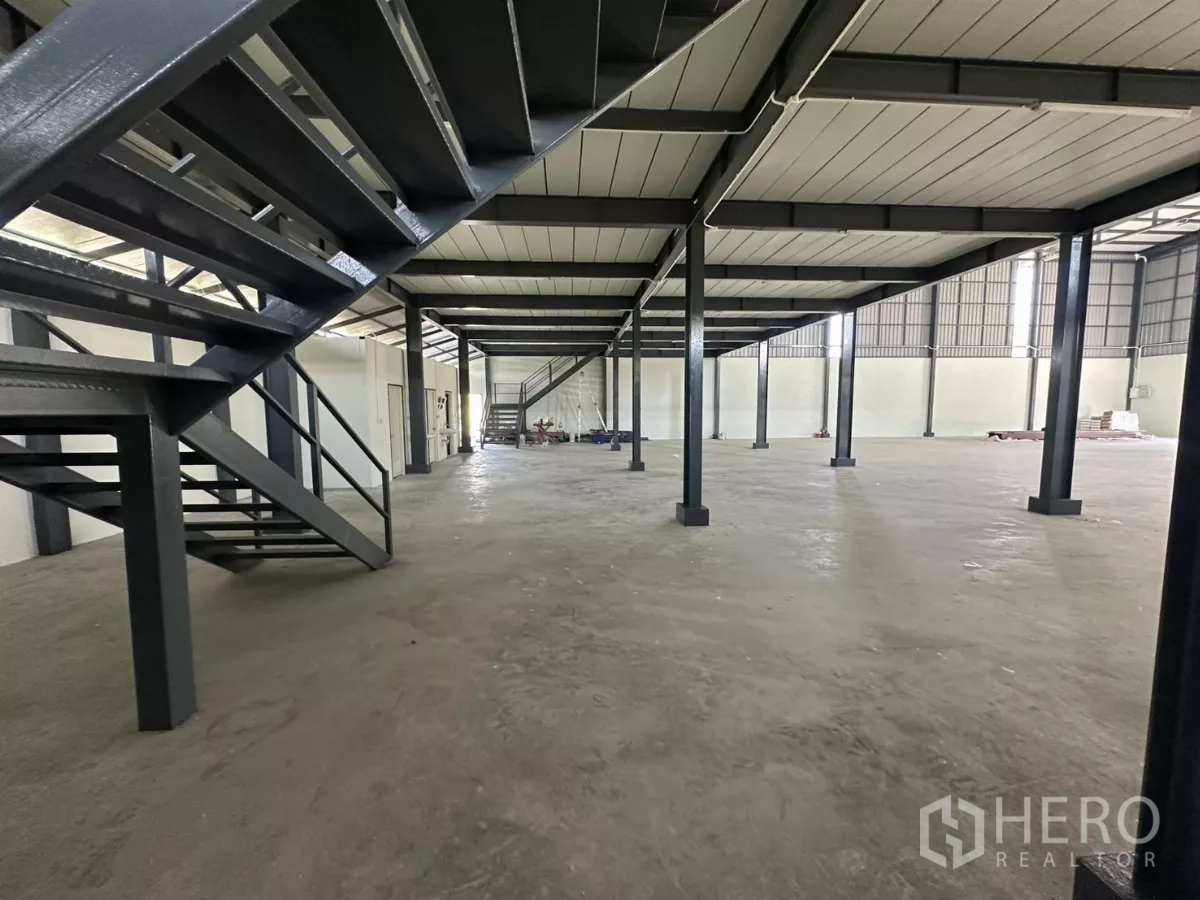 Warehouse for rent in Prawet, Bangkok - Under-mezzanine view with steel staircase and columns providing open floor space.