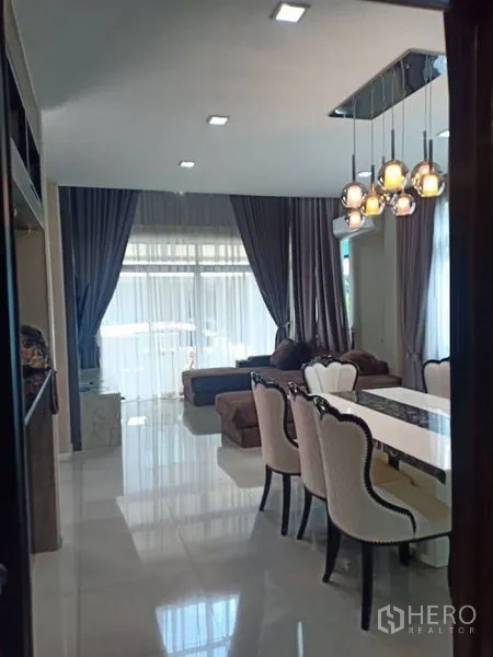 独立式住宅 出租在Thanyaburi, Pathum Thani - 开放式客餐厅，吊灯、沙发、纱帘与亮面地砖相映成趣。