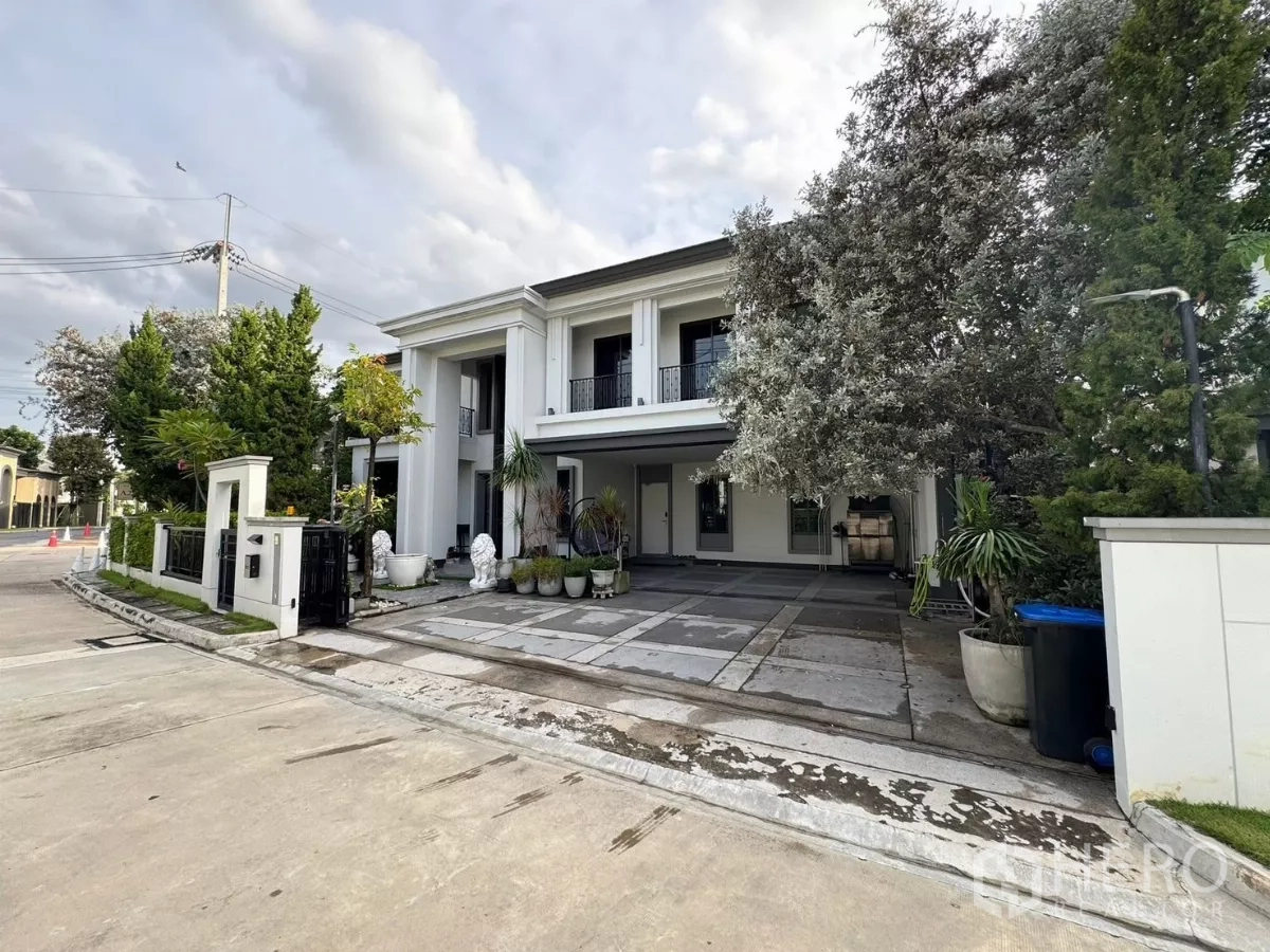 Detached House for sale in Mueang Pathum Thani, Pathum Thani - Corner plot view of the white detached house with wide driveway and black gate.