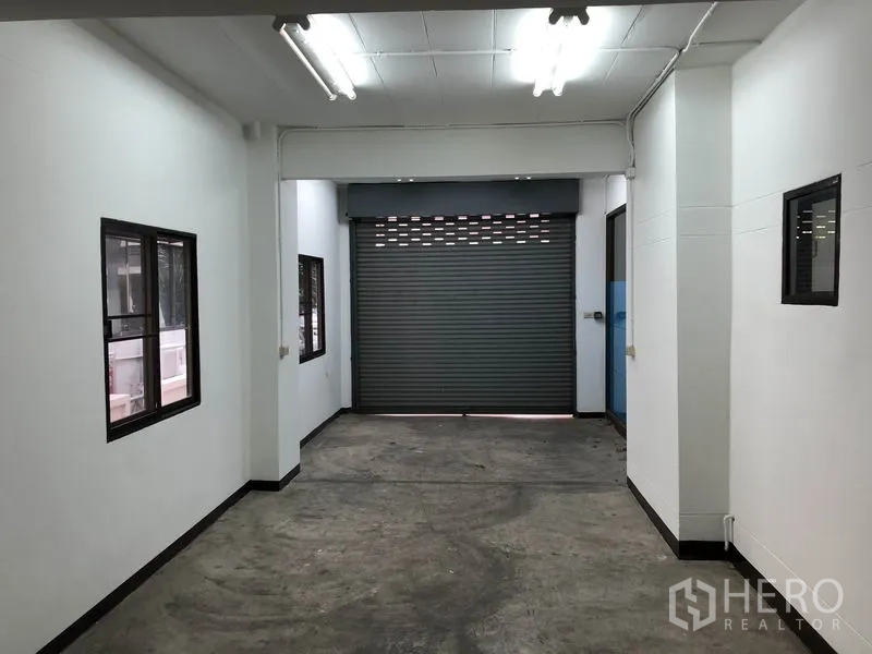 Home Office for rent in Huai Khwang, Bangkok - Covered parking or loading bay with roller shutter door, windows and fluorescent lighting.