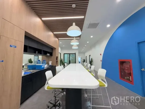办公空间 出租在Huai Khwang, Bangkok - 共享茶水间与休闲区，超长中岛吧台、吧椅与吊灯，木质装饰。