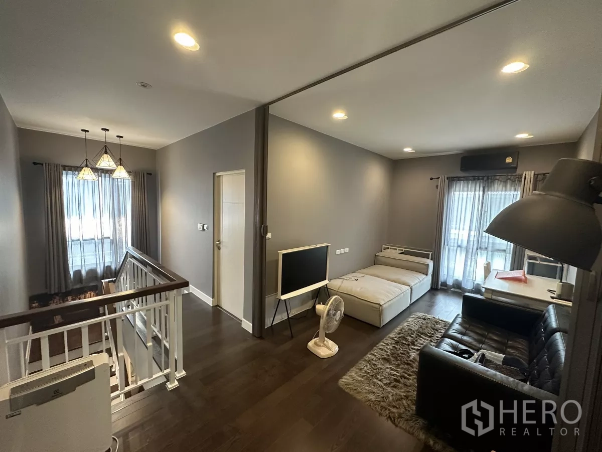 Detached House for rent or sale in Lam Luk Ka, Pathum Thani - Upstairs family room beside the staircase with daybed, sofa, pendant lights and balcony access.