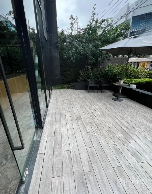 Retail Space for rent in Watthana, Bangkok - Outdoor terrace with wood-look tiles, seating and umbrella next to the glass facade.