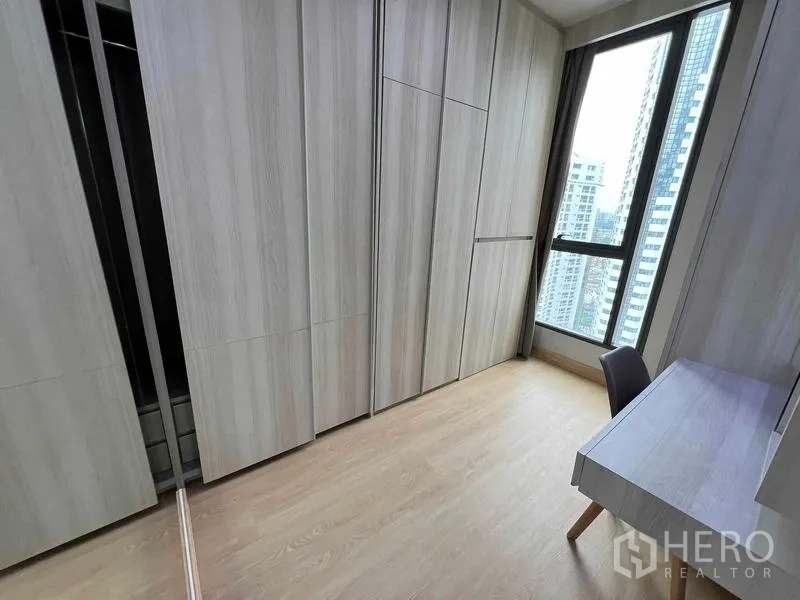 Condominium for rent or sale - Walk-in wardrobe room with full-height closets, desk, and city-view window.