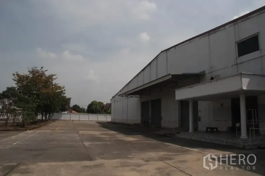 Warehouse for rent in Lam Luk Ka, Pathum Thani - Wide yard and covered loading bays at a large white warehouse in Lam Luk Ka.
