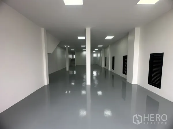 Warehouse for sale in Khlong Luang, Pathum Thani - Clean warehouse ground floor with epoxy-coated floor, white walls, columns and bright ceiling lights.
