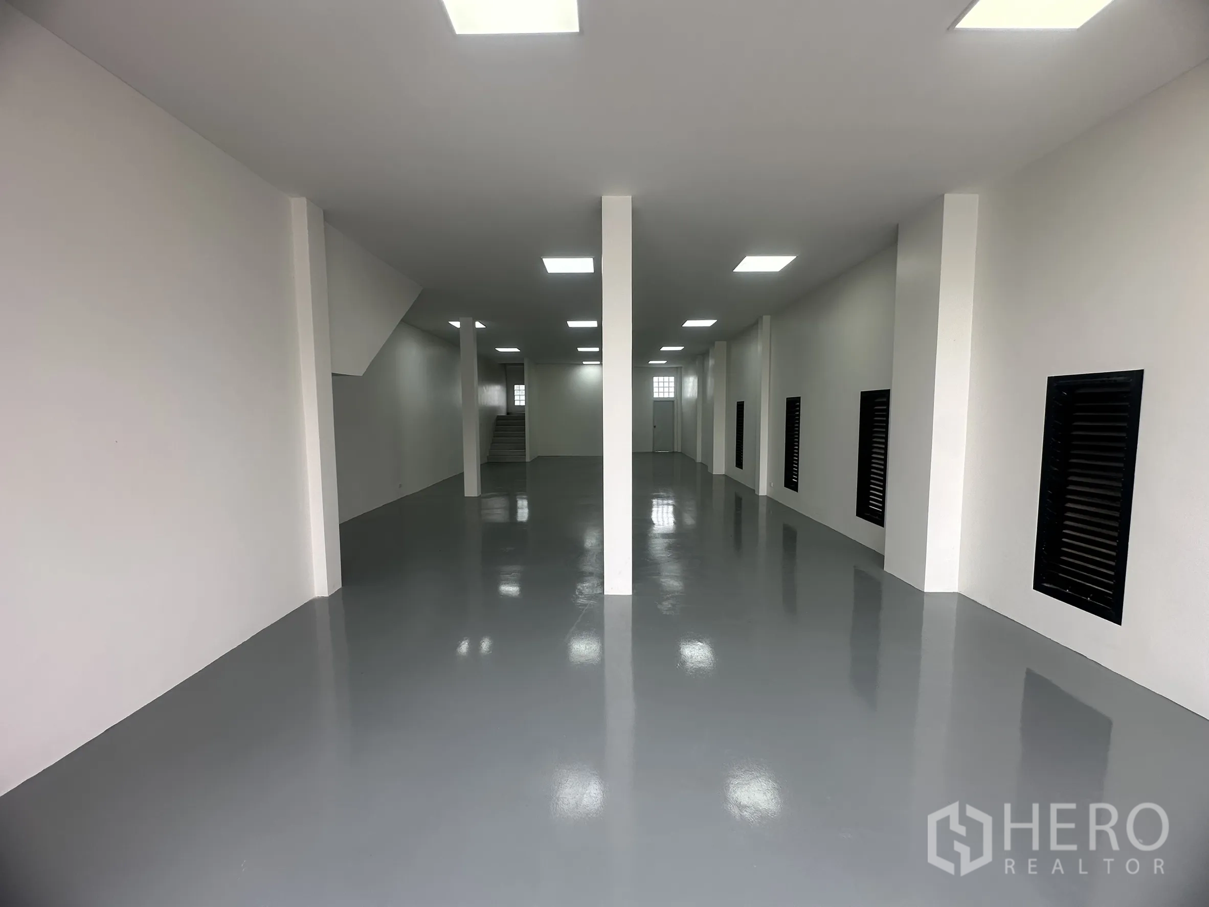 Warehouse for sale in Khlong Luang, Pathum Thani - Clean warehouse ground floor with epoxy-coated floor, white walls, columns and bright ceiling lights.