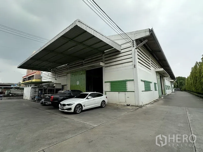 Warehouse for rent in Lat Krabang, Bangkok - Warehouse exterior with wide loading canopy, large shutter door and parking for cars and trucks.