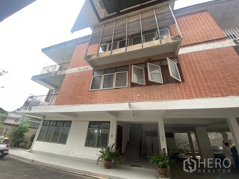 Home Office for rent in Khlong Toei, Bangkok - Three-story brick home office building with balconies and open windows in Bangkok.
