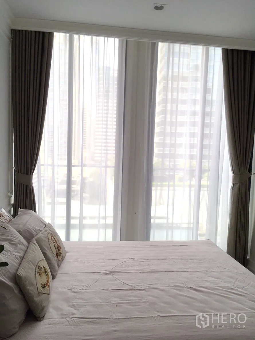 Condominium for rent in Pathum Wan, Bangkok - Sunny bedroom with double bed, sheer curtains, and floor-to-ceiling city-view windows.