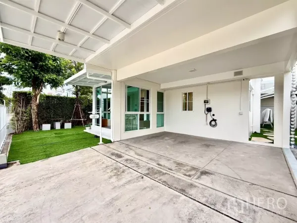 Detached House for rent in Bang Phli, Samut Prakan - Covered two-car garage with EV charger facing lawn and hedge.