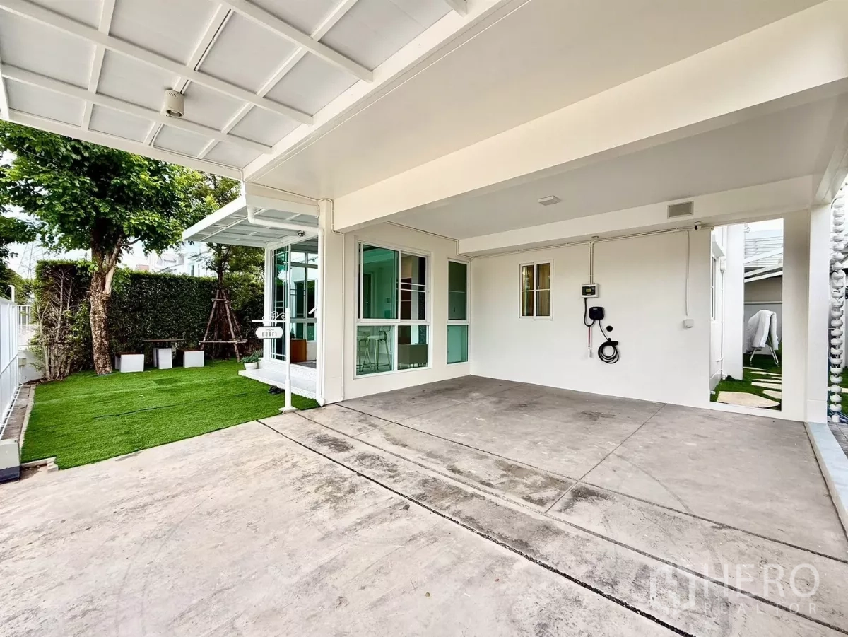 Detached House for rent in Bang Phli, Samut Prakan - Covered two-car garage with EV charger facing lawn and hedge.