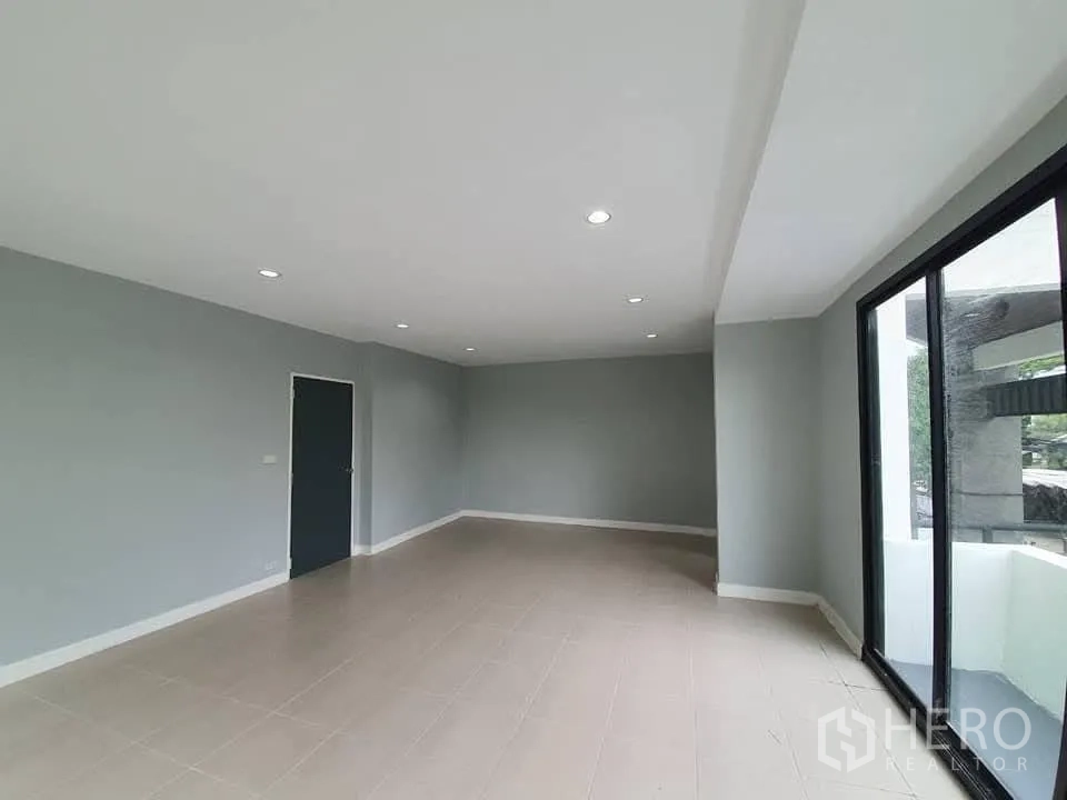 Home Office for rent in Wang Thonglang, Bangkok - Corner office room with large window and sliding door to balcony in neutral tones.