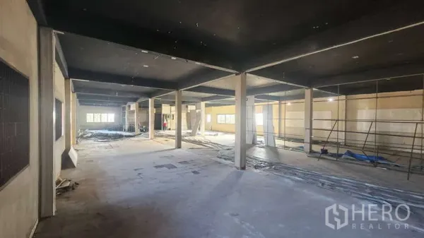 Factory for rent in Chom Thong, Bangkok - Spacious workshop area with dark ceiling, support columns and side windows.