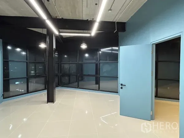 Office Space for rent in Chatuchak, Bangkok - Corner workspace featuring floor-to-ceiling grid windows, black steel columns, blue walls and an open ceiling.