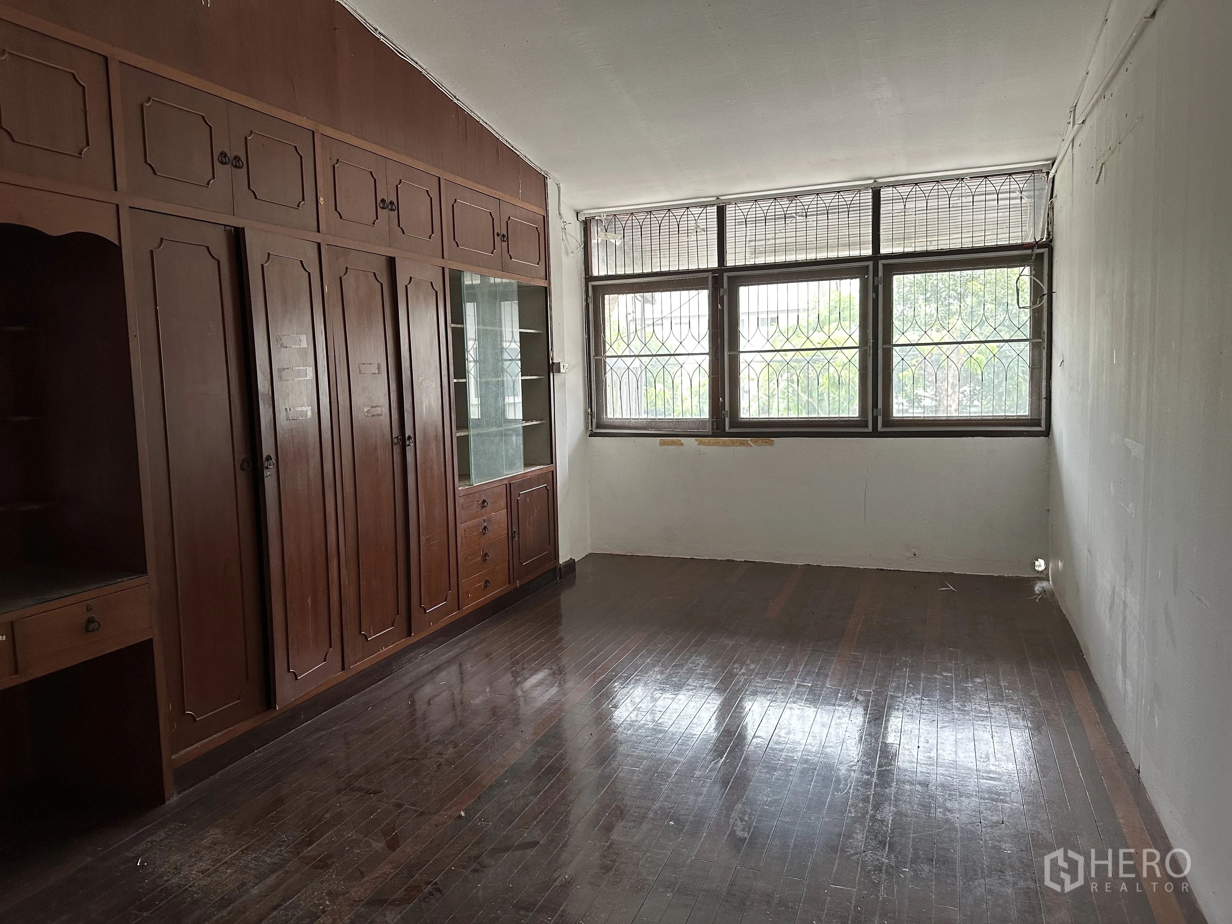 Home Office for rent in Suan Luang, Bangkok - Upper room with built-in wooden cabinets and large windows with metal bars.
