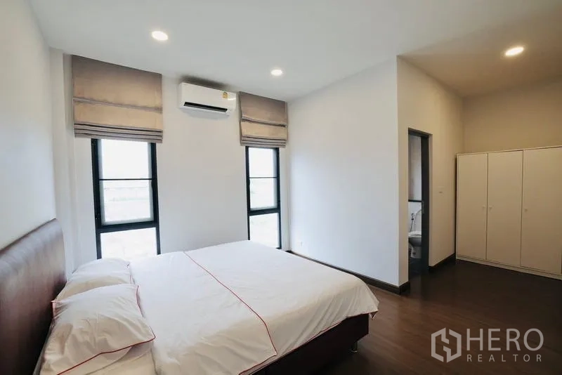 Detached House for rent in Bang Phli, Samut Prakan - Bedroom with bed, two tall windows, wardrobe, and ensuite doorway.