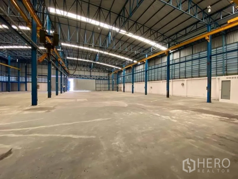 Factory for rent or sale in Bang Sao Thong, Samut Prakan - Spacious factory interior with high steel truss roof, concrete floor, and overhead crane rails.