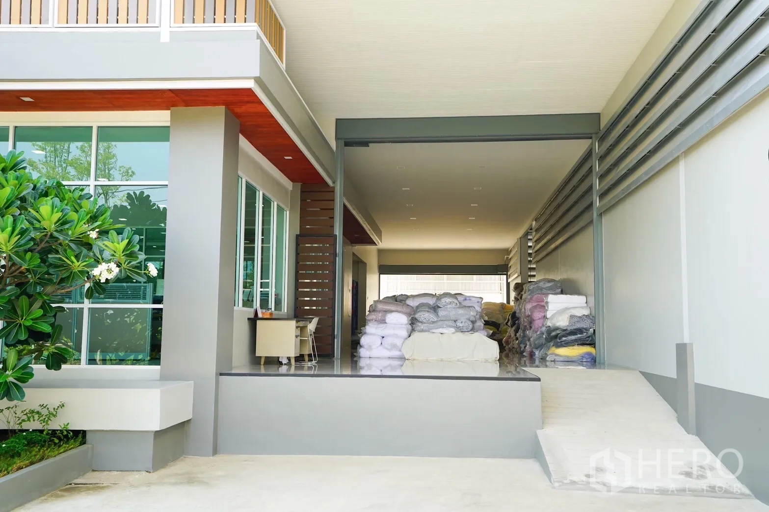 Factory for sale in Krathum Baen, Samut Sakhon - Covered loading dock with ramp next to a glass-walled office building.