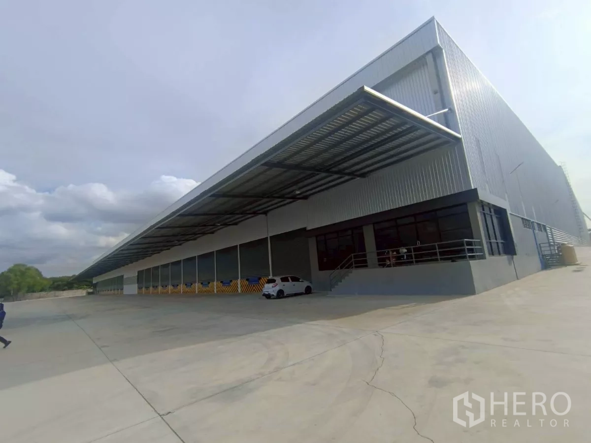 Factory for rent in Si Racha, Chon Buri - Corner view of the warehouse showing canopied loading bays, shutter doors and generous truck circulation space.
