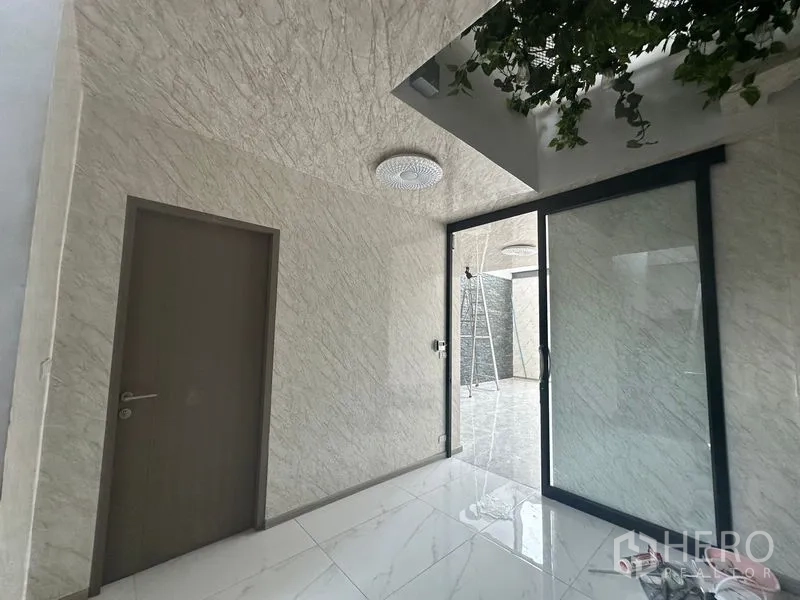 Home Office for rent - Entrance lobby with marble walls, sliding glass door and ceiling greenery.