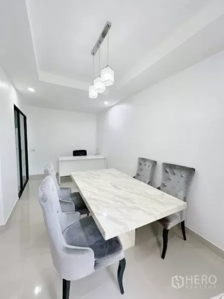 Townhouse for rent in Bang Phli, Samut Prakan - Minimal white dining room with pendant lights, marble table and grey tufted chairs.